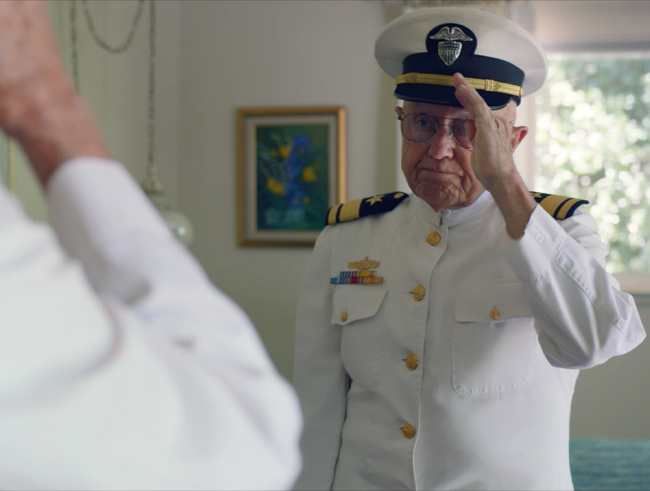 A senior veteran in a military dress uniform saluting himself in the mirror